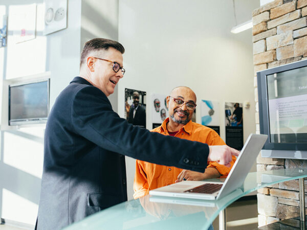 Two men discussing work on a laptop.