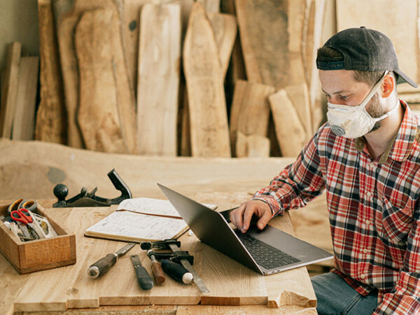 Woodworker using laptop in workshop