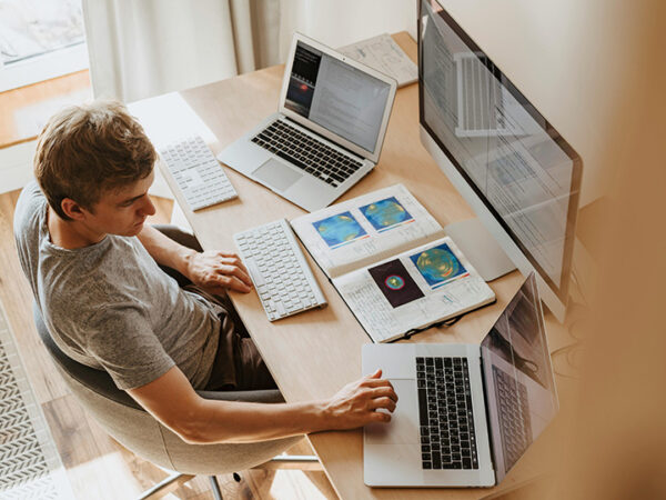 Man working with multiple computers and notebooks